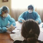 Healthcare professionals in PPE discuss operations during a meeting indoors.