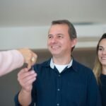 Smiling couple receiving keys, celebrating new home purchase indoors.
